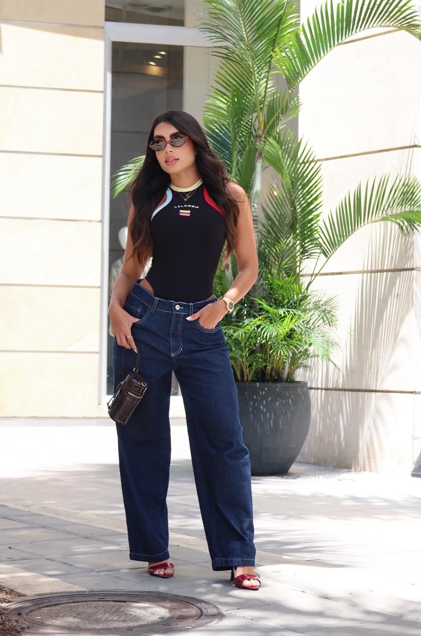 Modelo con body y jean de pierna ancha frente a una fachada de piedra